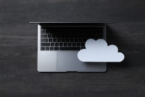 White paper cloud with laptop on black table background